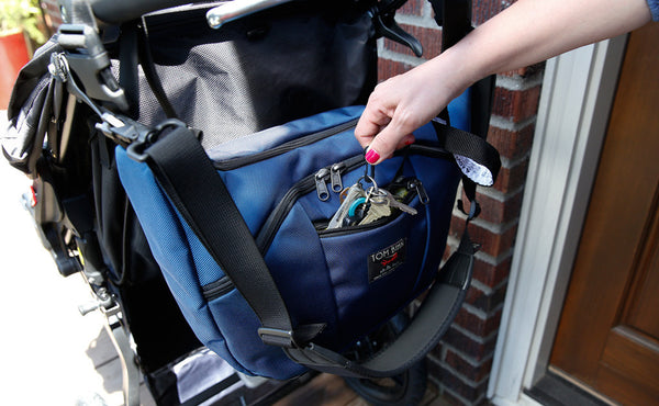 A person retrieving keys from a Parental Unit hung to a stroller using the Stroller/Wheelchair Strap.